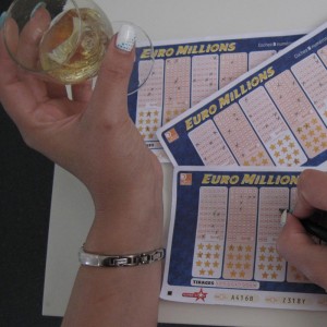 Photo prétexte: personne buvant du vin et remplissant de nombreux bulletins de lotterie
